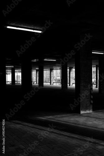 Dark parking garage interior with concrete pillars and fluorescent lights