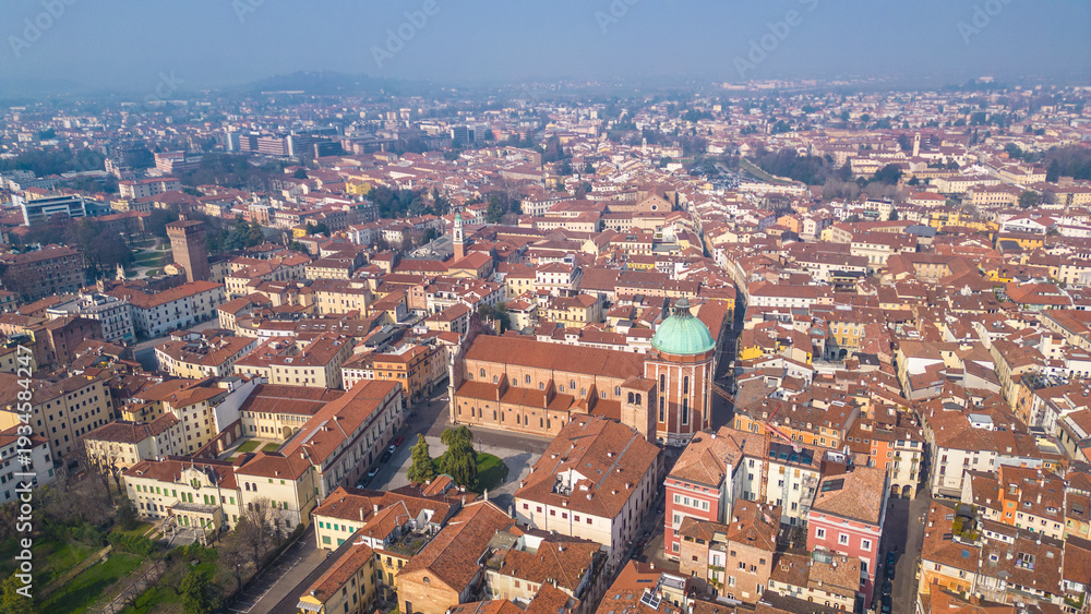 Obraz premium An aerial view of Vicenza, Italy, showcasing its historic city center, terracotta rooftops, and the iconic Basilica Palladiana under a clear winter sky. UNESCO World Heritage site.