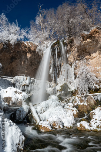 Rifle Falls amidst snow and ice formations in Rifle Falls State Park, Colorado on exceptionally cold clear sunny winter morning.