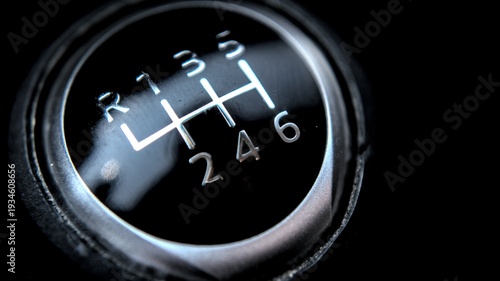 Extreme closeup of a manual transmission gear shifter showing reverse and six forward speed indicators