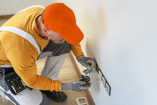 Electrical installation. An electrician's hands during installation a wall sockets to multi pack socket. 