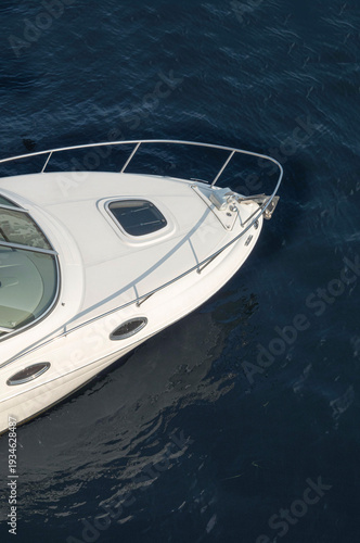 Boat bow, front of a modern white yacht in water seen from above.