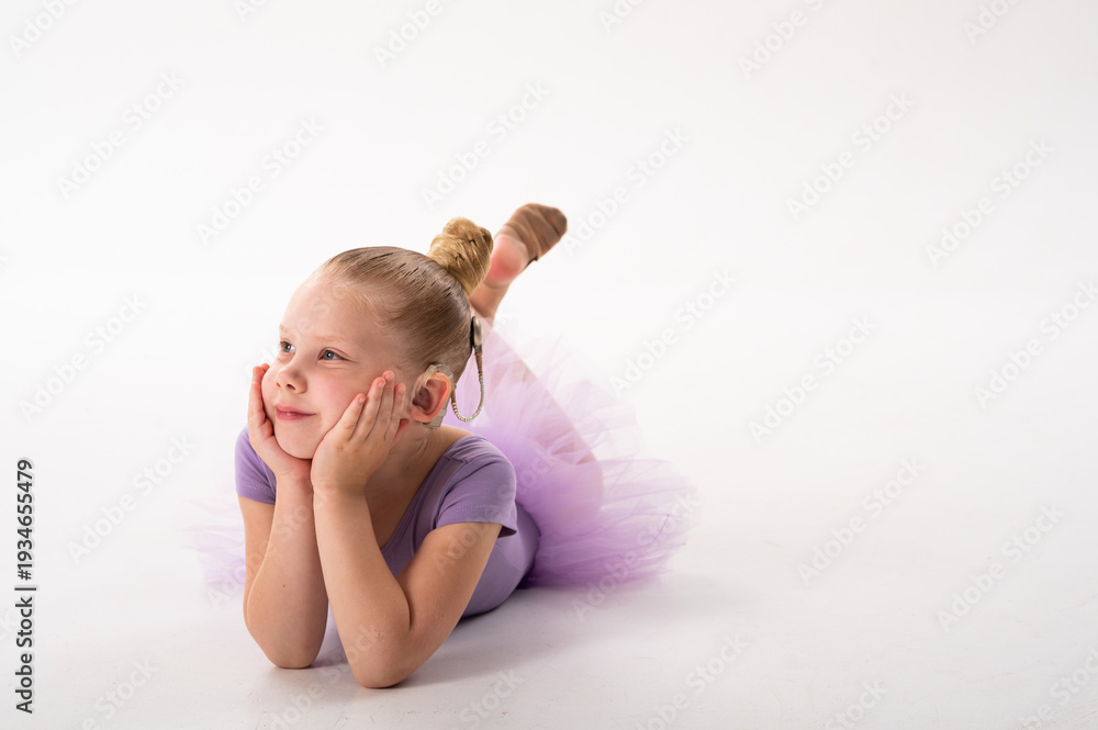 Naklejka premium Girl with cochlear implant lying and smiling to the side. Hearing recovery, childhood confidence, and inclusion in modern education and art.