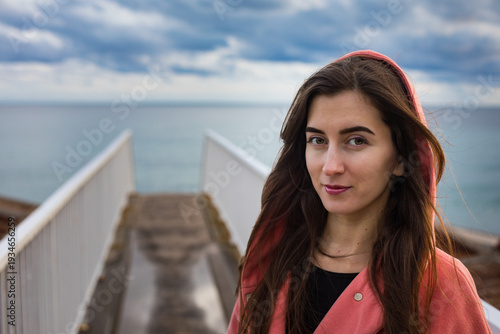 a girl in a coral coat against the backdrop of the sea in autumn