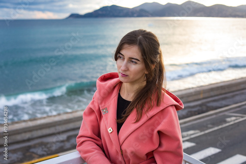 a girl in a coral coat against the backdrop of the sea in autumn
