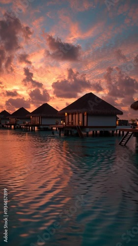 Overwater bungalows bask in a fiery sunset over calm turquoise waters
