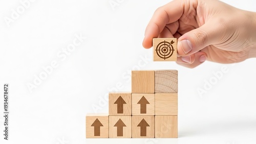 Hand placing growth target block on wooden arrow stack for business success strategy