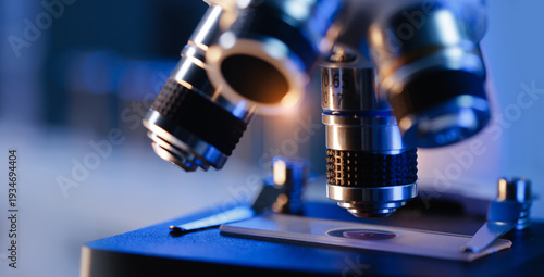 Photos Close-up of microscope lenses focusing on slide in laboratory setting