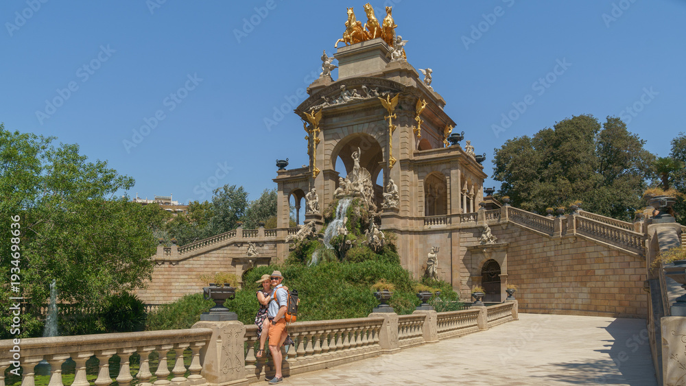 Obraz premium Romantic couple embraces by the majestic Cascada del Parc de la Ciutadella, Neptú and Quàdriga de l’Aurora in Barcelona, Catalunya (Spain), ideal for summer travel campaigns.