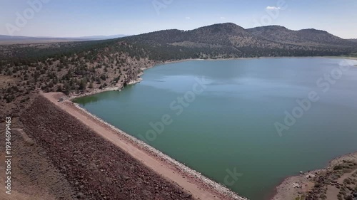 Aerial drone footage over a nearly full reservoir in an arid western landscape.