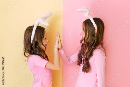 Fotografie A girl dressed up as Easter bunnies gives a high five