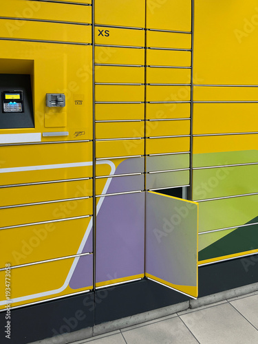 Bright yellow parcel locker with an open compartment, touchscreen interface, and colorful geometric design, representing modern self-service package pickup.