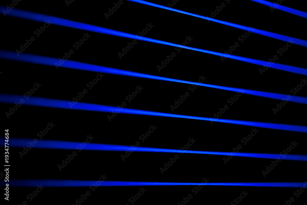 Fototapeta premium Thin blue lines slice a black field. Laser lines.