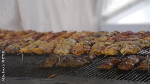 This video shows a close up view of delicious chicken skewers cooking on a grill.
