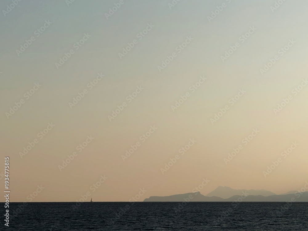 Fototapeta premium Minimalist landscape composition with a narrow strip of sea at the bottom edge. Sailboat silhouette on horizon line. Mountains. A vast expanse of soft gradient sky during sunset. Calm and serene.