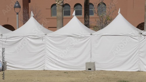 This panning video shows a row of white vendor tents being set up with no people.