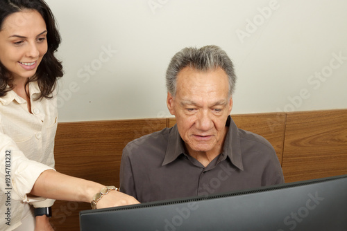 Senior man working on a computer with a young woman team leader 