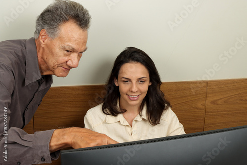 Senior man and a young woman colleague working together on a computer 