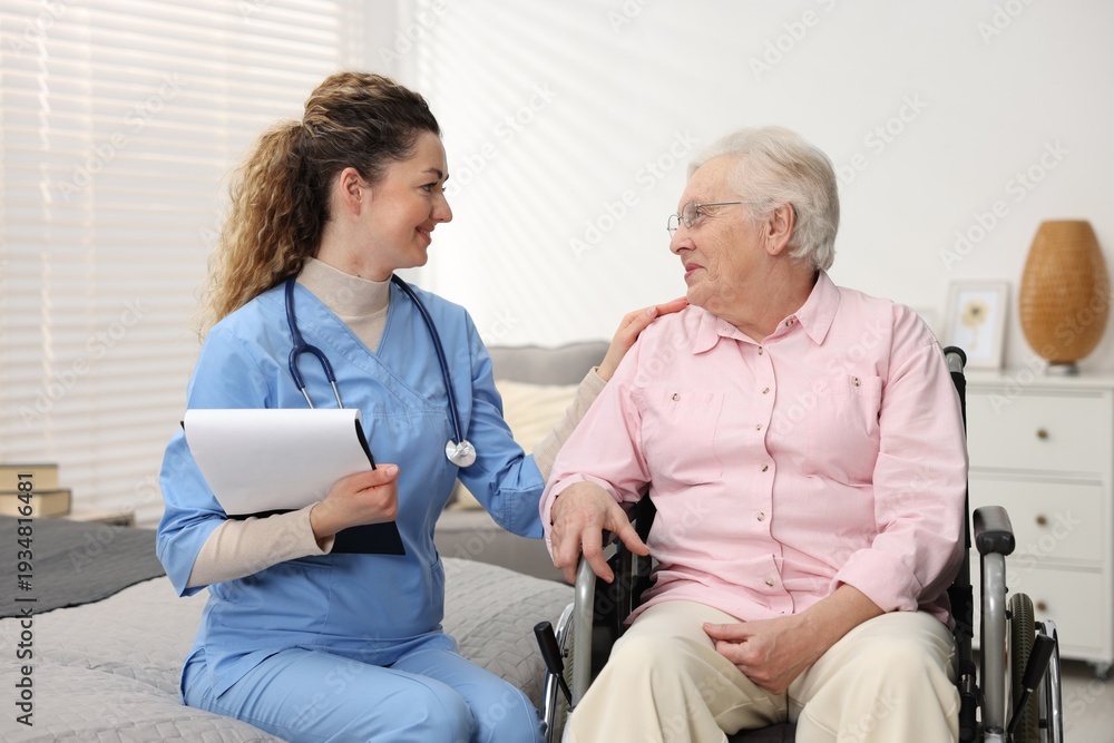 Obraz premium Care worker supporting senior woman in wheelchair indoors