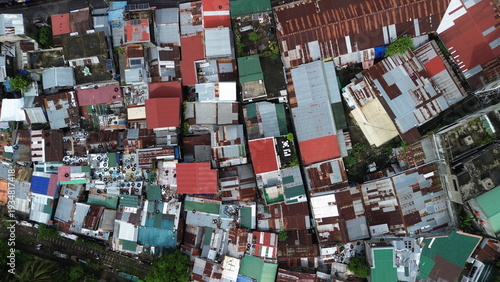 Aerial top-down view of dense urban informal settlement with rusted metal roofs beside a railway track
