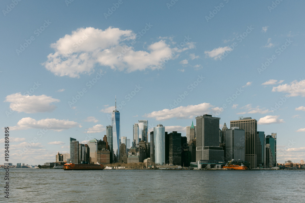 Obraz premium View of Lower Manhattan skyline with boats in the water on a sunny day with clouds in the sky