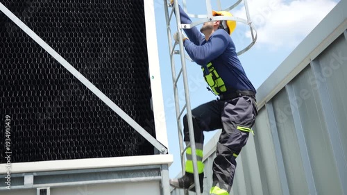 Maintenance worker in safety gear ascending ladder for industrial cooling system inspection, Industrial technician climbing safety cage ladder to perform high-altitude maintenance