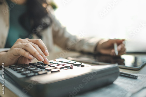 Fotografie Businesswoman using calculator and tablet for corporate finance analysis, representing budget planning, financial report evaluation and investment strategy management concept