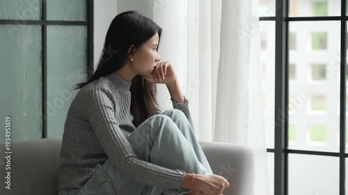 Young Asian Woman Feeling Sad and Lonely Thinking about Problems on Sofa at Home
