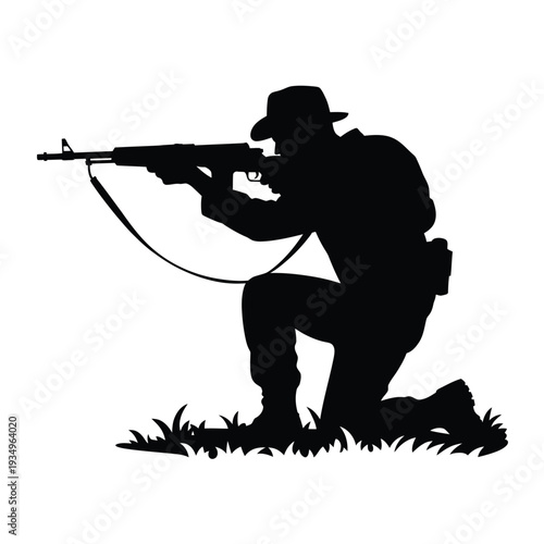 Silhouette of a soldier kneeling aiming a rifle in a grassy area