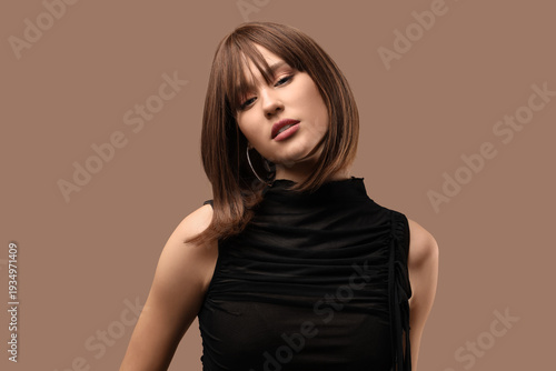 Beautiful young woman in short wig on beige background
