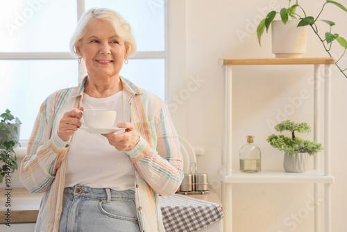 Senior woman with cup of tea in kitchen