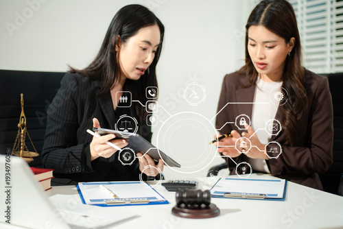 Asian women lawyers reviewing contract documents on tablet, discussing legal compliance, finance, cybersecurity and corporate business strategy