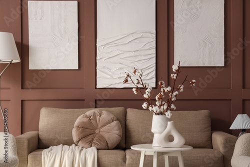 Interior of stylish living room with grey sofa, table and paintings
