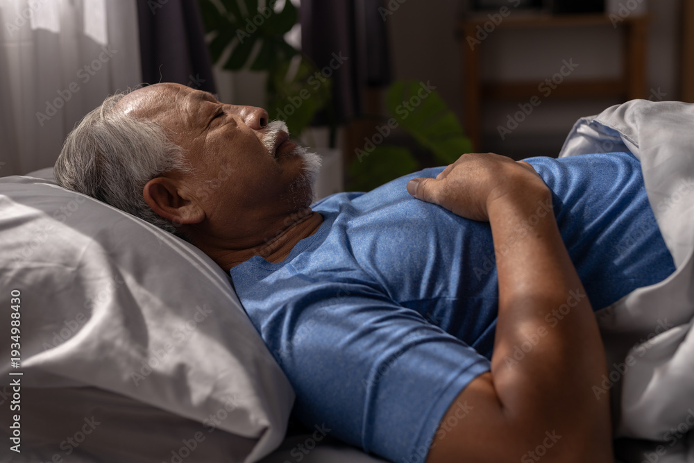 Fototapeta premium Senior man sleeping peacefully in bed at night in cozy bedroom, hands on chest. Concept of healthy sleep, rest, aging lifestyle, bedtime routine, relaxation and senior health care at home.