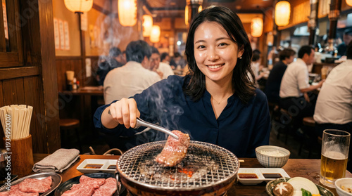 焼肉店でトングを使い肉を焼く笑顔の日本人女性