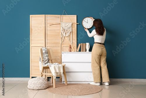Young woman hanging clock o...