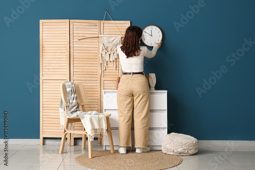 Young woman hanging clock o...