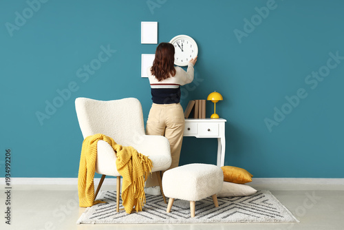 Young woman hanging clock o...