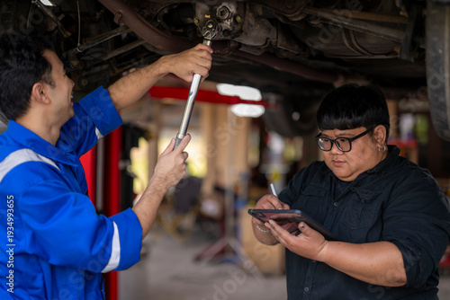 Quadro em tela Auto mechanics team inspecting car underside using digital tablet