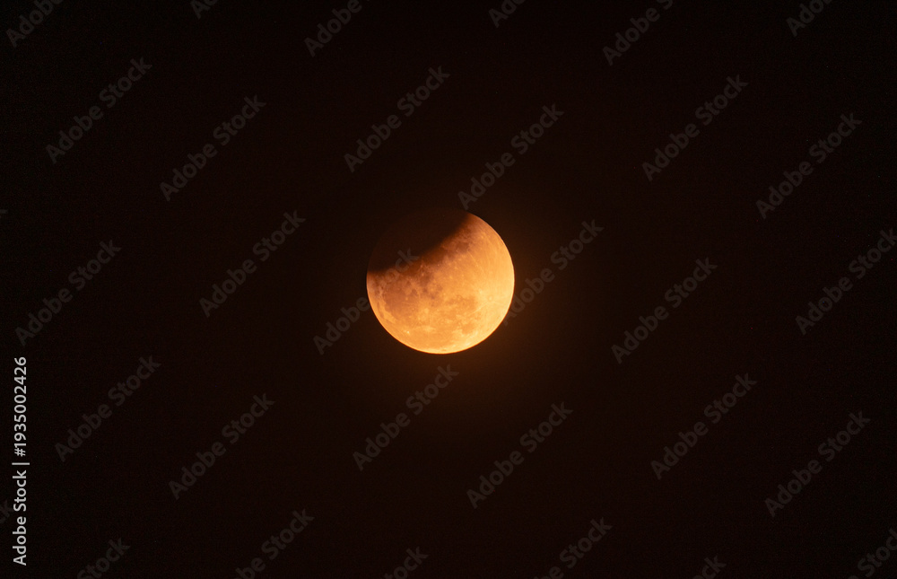 Naklejka premium The Worm Moon total lunar eclipse, the last full moon of winter, the Moon moves from right to left as it passes through Earth's shadow. The Moon was taking on a coppery red hue, known as