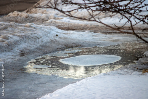 Ice forming in a puddle at dusk during winter
