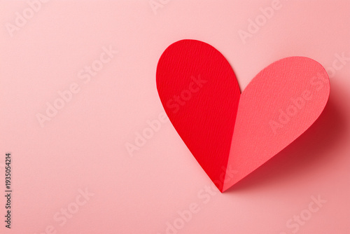 Handmade red and pink paper heart on pastel pink background for valentine's day or love themed designs and greeting cards
