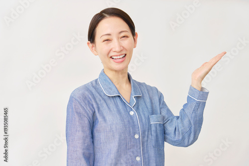 Fotografie パジャマを着た女性　手のひらで右を指す　白バック