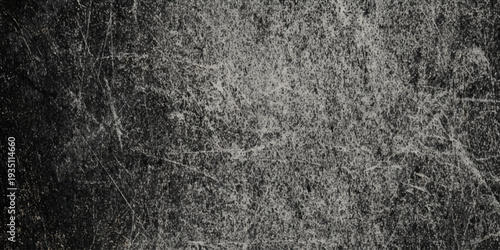 A heavily wall textured monochromatic image displaying a dark and gritty surface with irregular patterns and subtle tonal variations