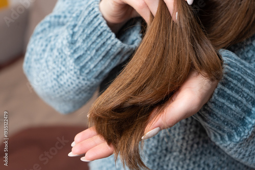 Photos Woman showing split ends on dry winter hair in cozy sweater