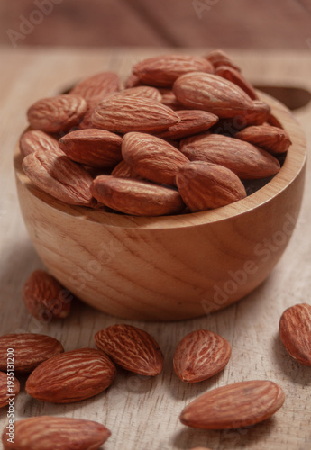 Almonds placed in a wooden cup and on a natural wood plate, highlighting simple organic textures.