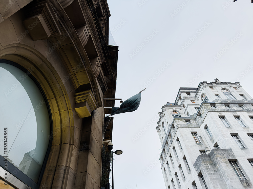 Obraz premium Flag on a grand stone storefront in Manchester UK showcasing architectural contrast