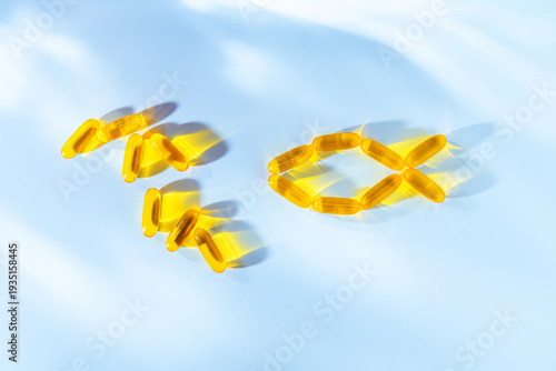 Golden omega 3 fish oil capsules arranged in the shape of a fish on blue background, symbolizing dietary supplements, vitamins and healthy nutrition for well being