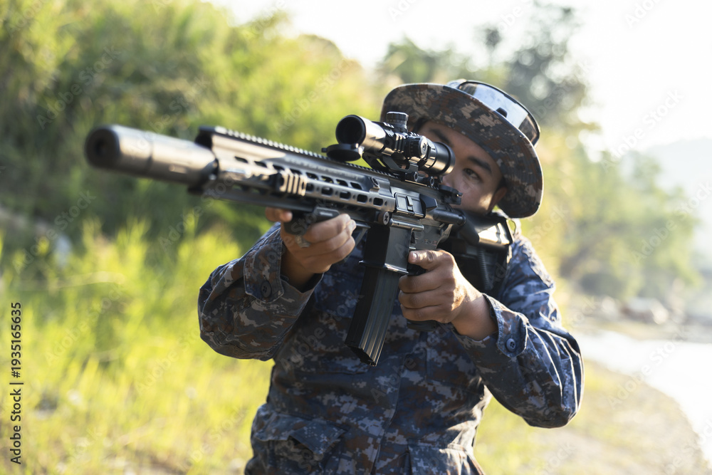 Obraz premium Focused soldier in camouflage aiming tactical rifle during military combat mission outdoor. special force operative with weapon showing concentration and precision