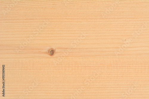 A horizontal close up of a light natural pine wood surface featuring a small dark knot and a fine linear grain pattern
